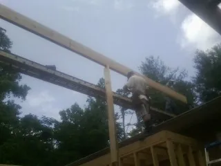 Carpenter setting a ridge beam over a new addition frame — Ice Dam Removal by Roofing Brothers in Hinckley