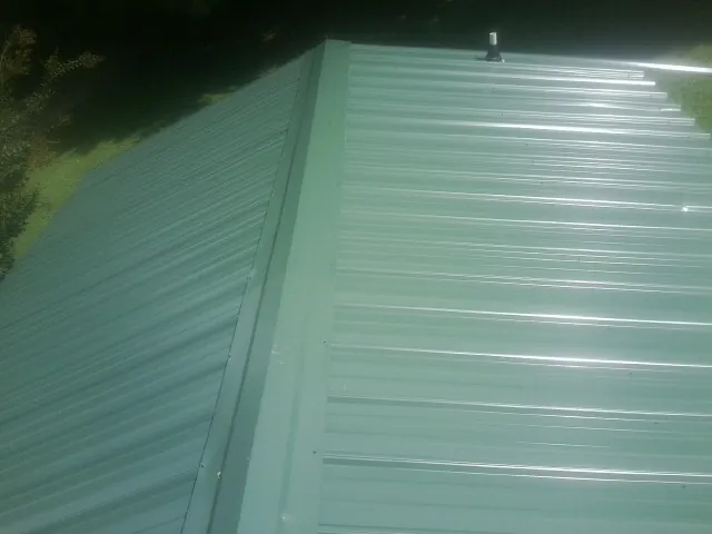 New green metal panels meeting at the ridge of a roof — Flat Roof Repair work by our crew in Hinckley