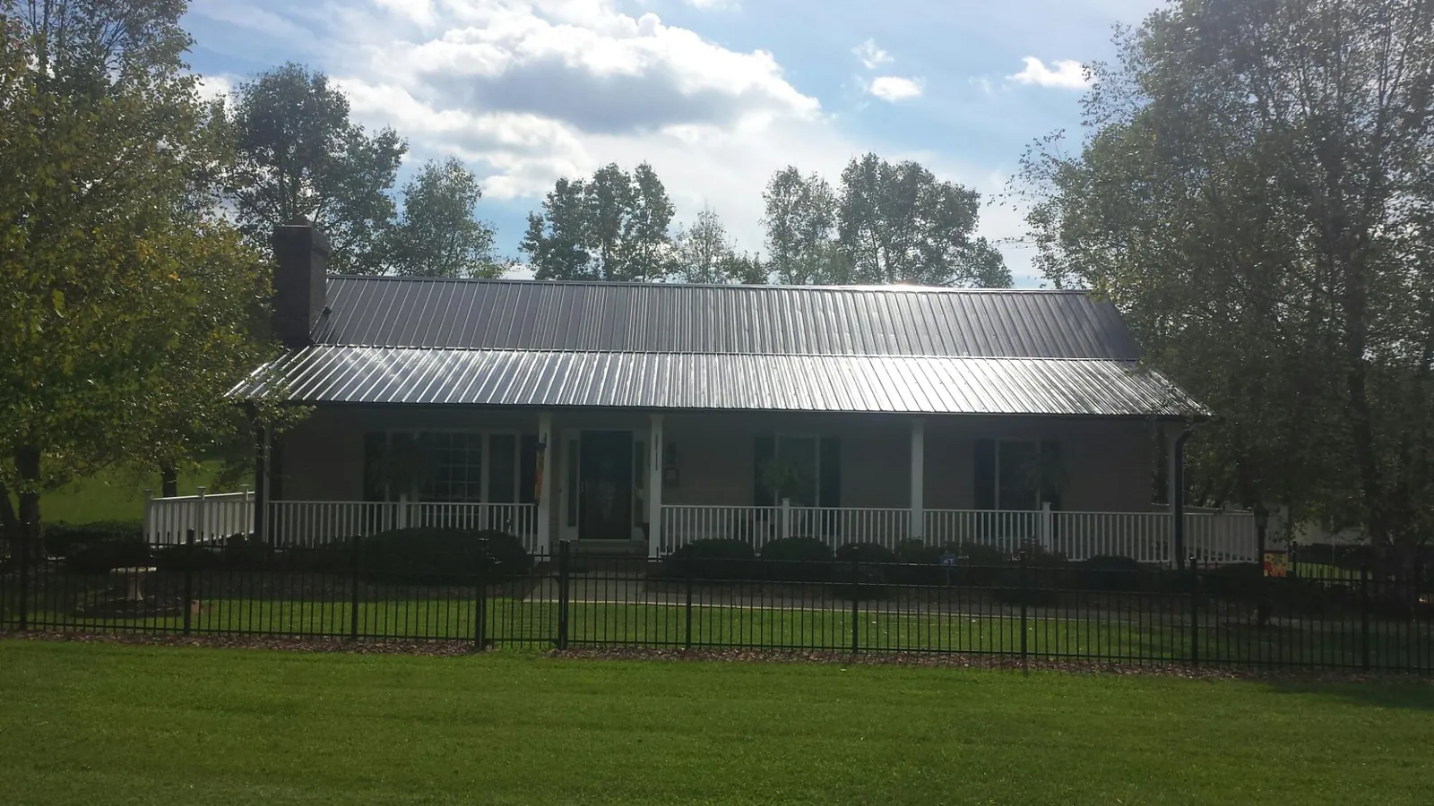 Gray metal roof on a brick ranch with a full width front porch — Gutter Guard Installation work by our crew in Hinckley