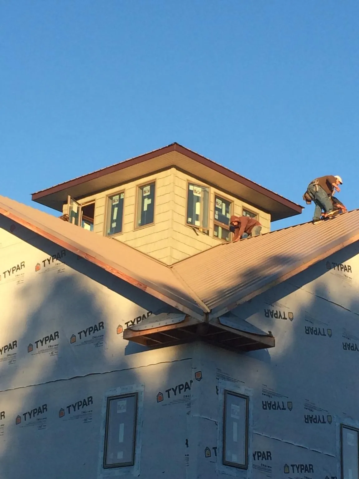 Roofers working around a rooftop cupola on a new metal roof at sunset — Roof Waterproofing in Hinckley by Roofing Brothers